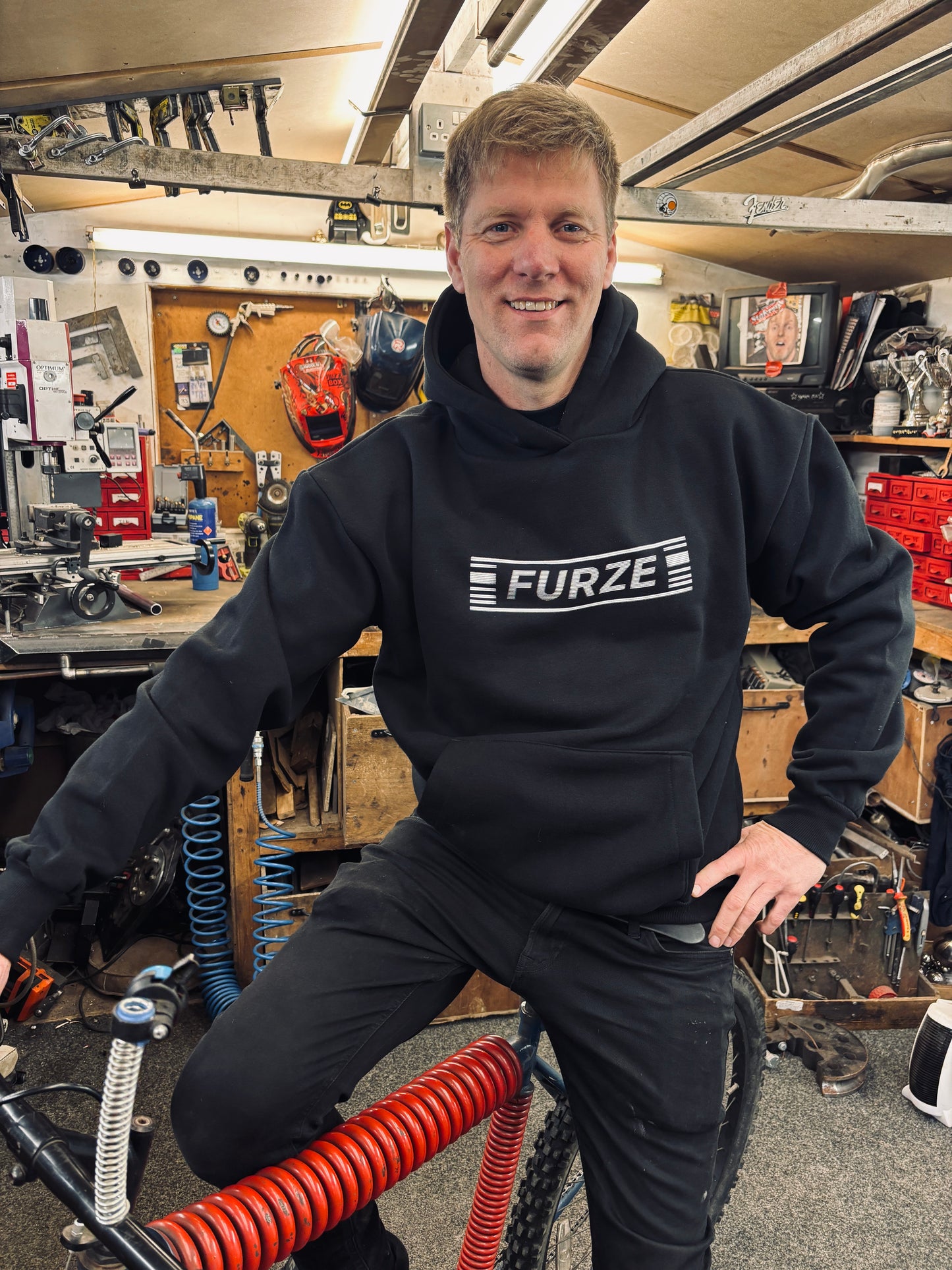 Colin sports the TV Static Hoodie set on a bike in his workshop