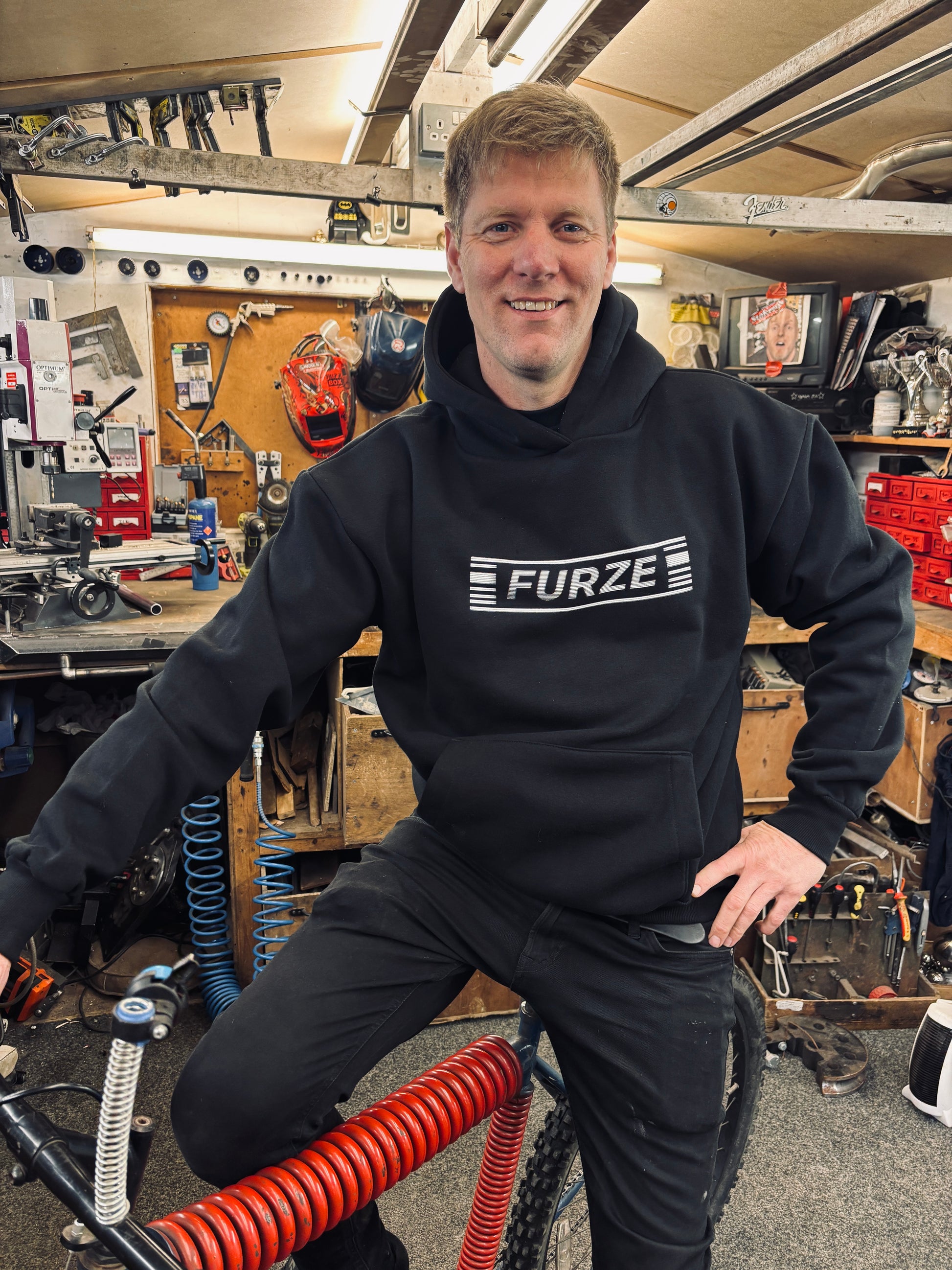 Colin sports the TV Static Hoodie set on a bike in his workshop