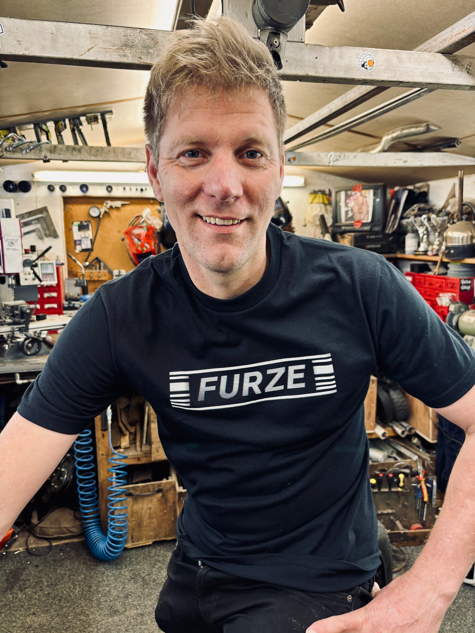 Colin wearing a black t-shirt with 'FURZE' logo in his workshop